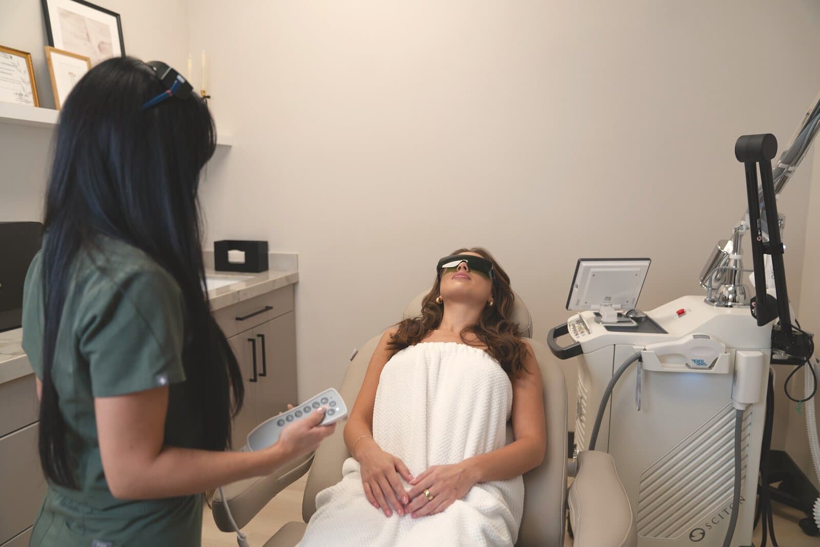 A provider settles a guest into the treatment chair beside the BBL BroadBand Light platform