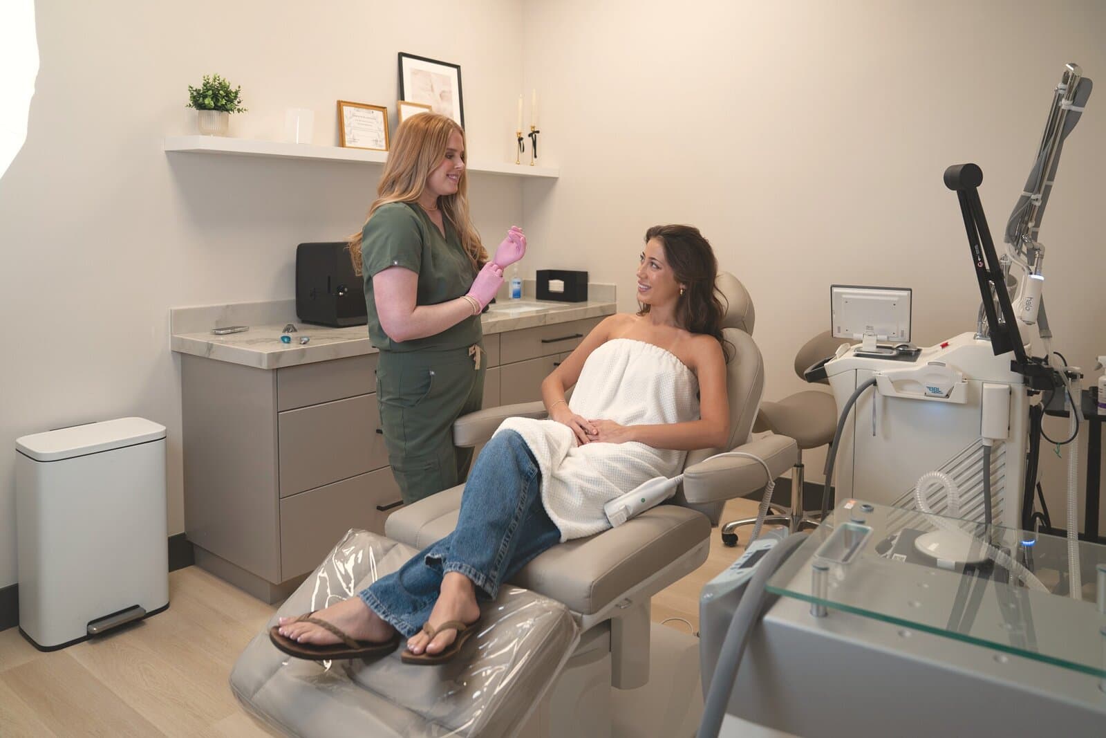 A team member in scrubs talks with a guest seated in the treatment chair
