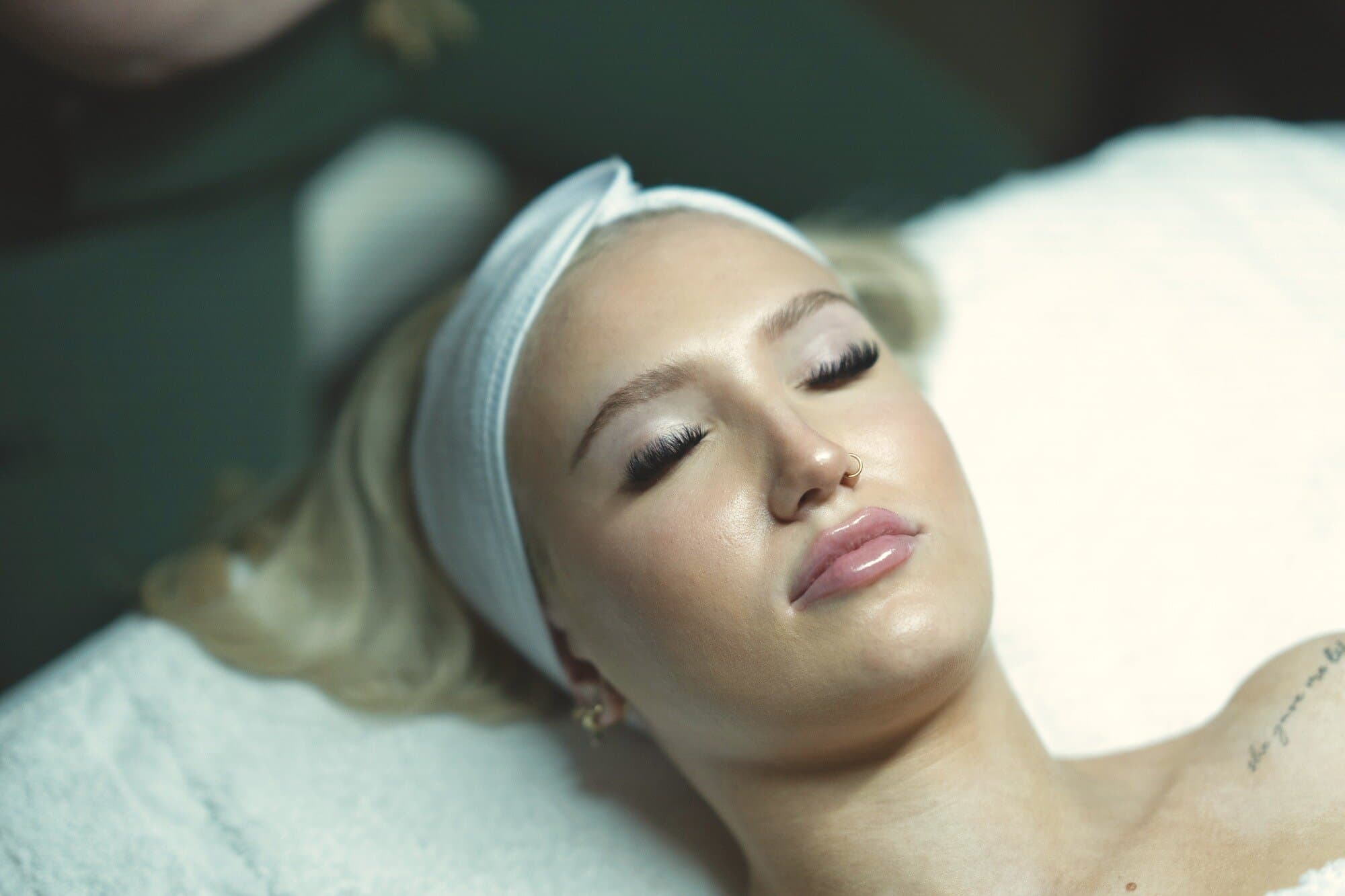 A guest resting in a headband on the treatment bed, eyes closed