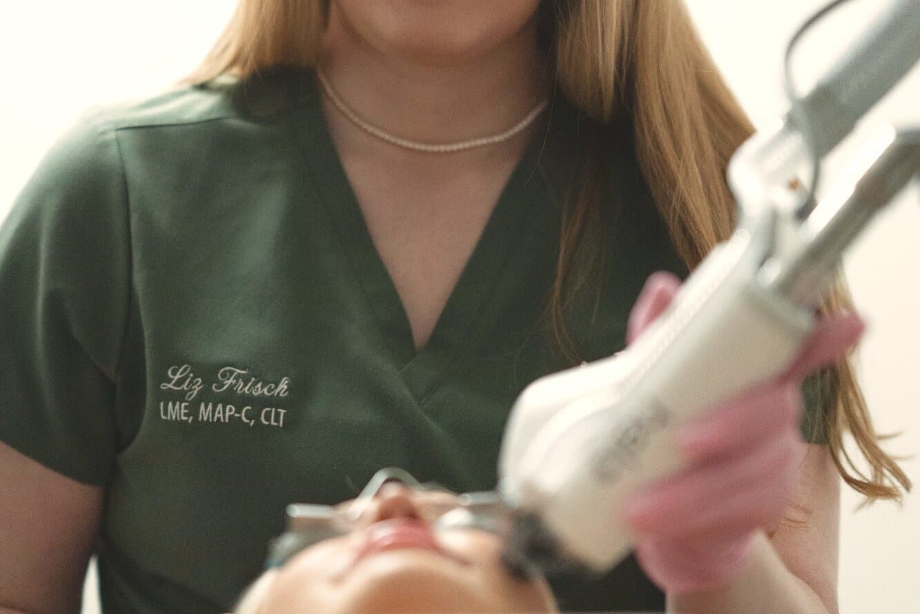 A provider in protective eyewear guides the HALO handpiece over a guest's face
