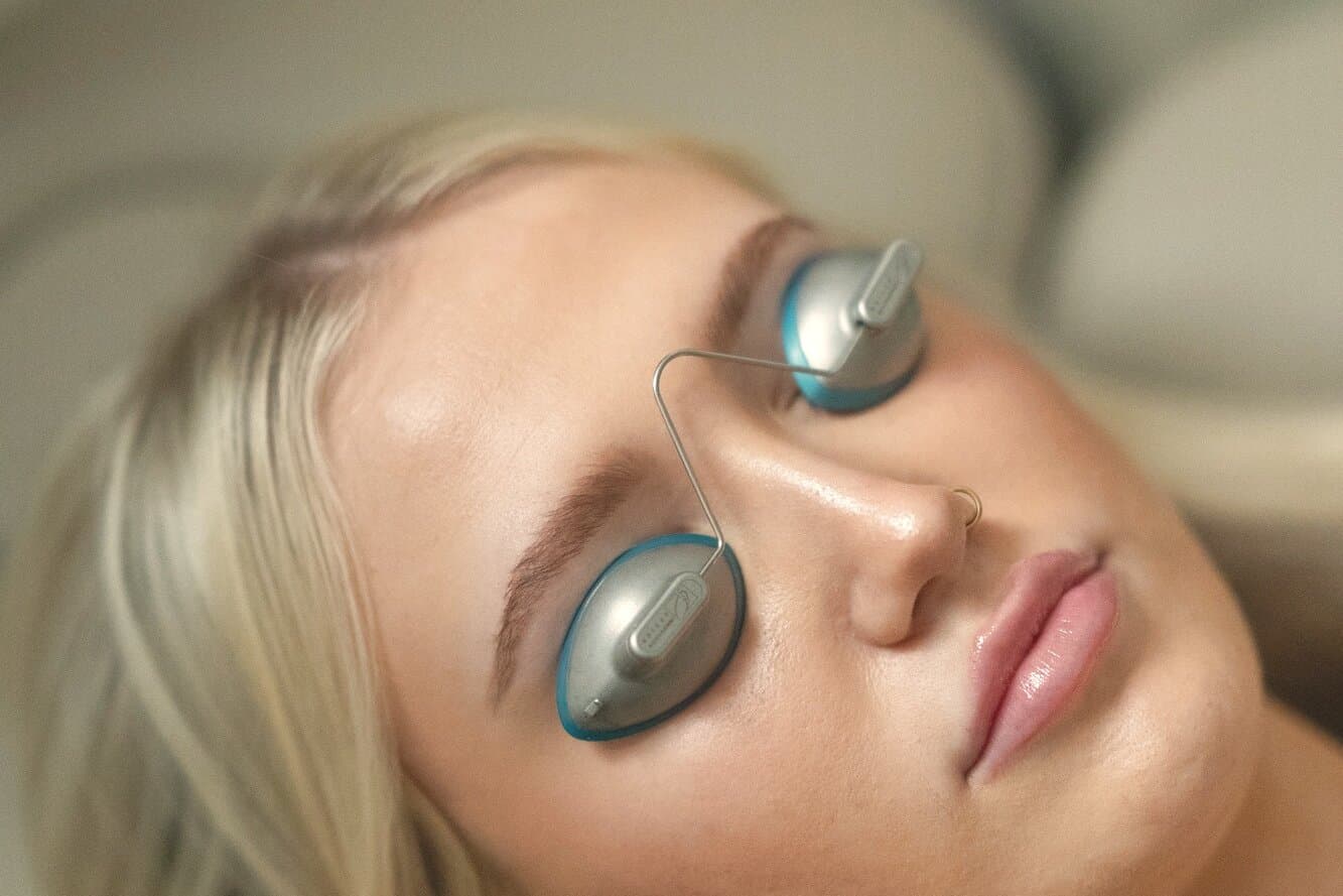 A guest reclined in the treatment chair wearing metal eye shields