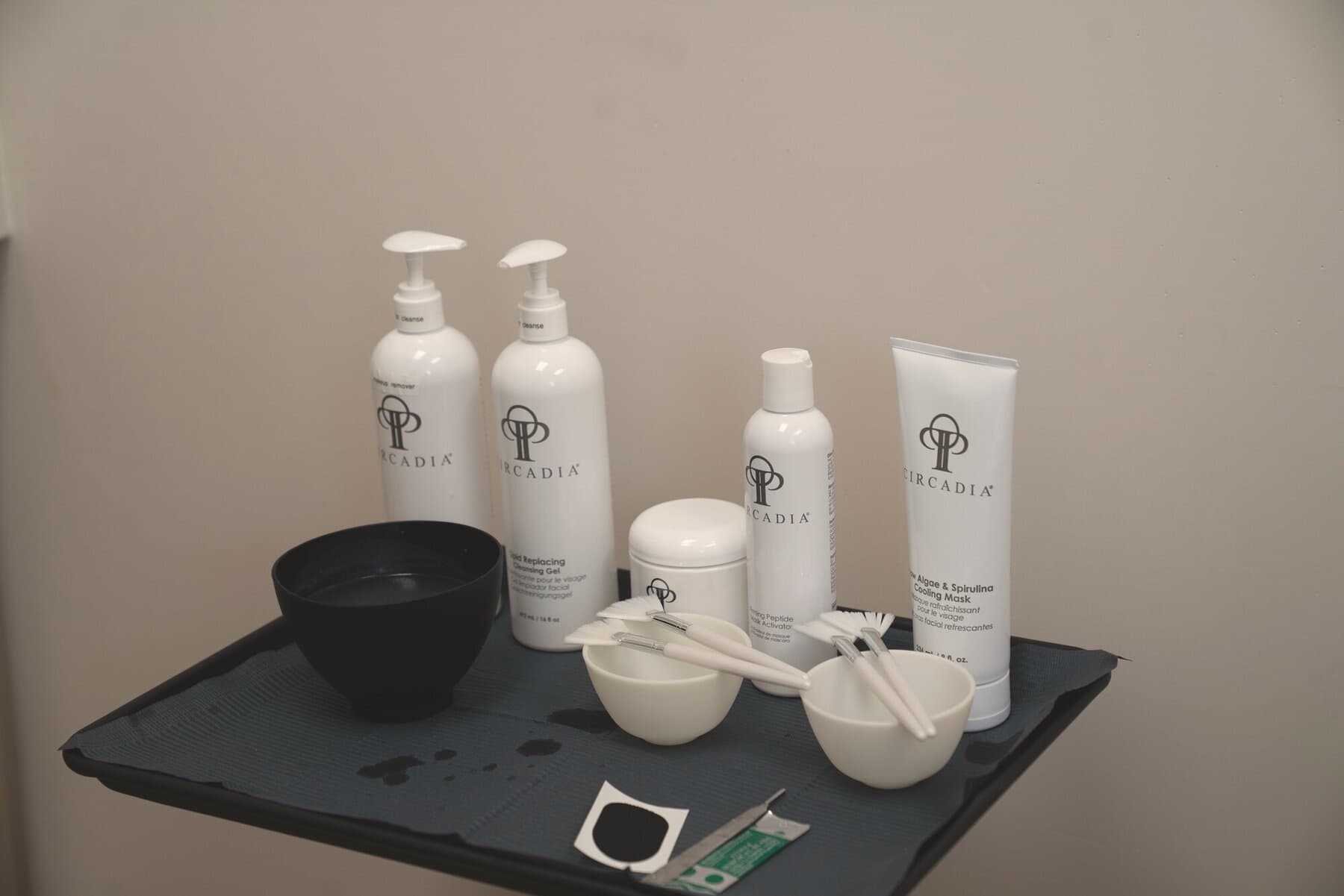 The treatment-room product tray: bottles, a mixing bowl and brushes laid out on a dark cloth