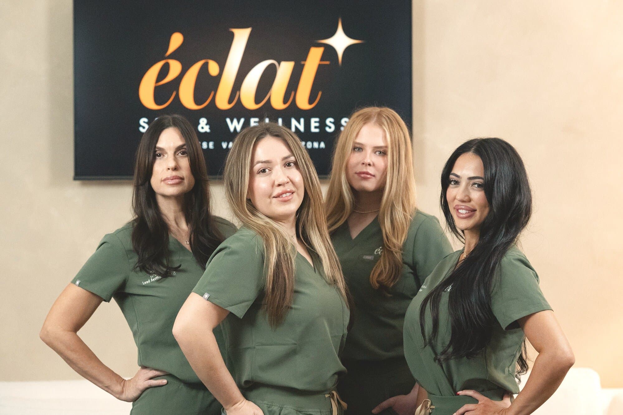 The team at éclat Spa & Wellness, in olive scrubs beside the lobby sign